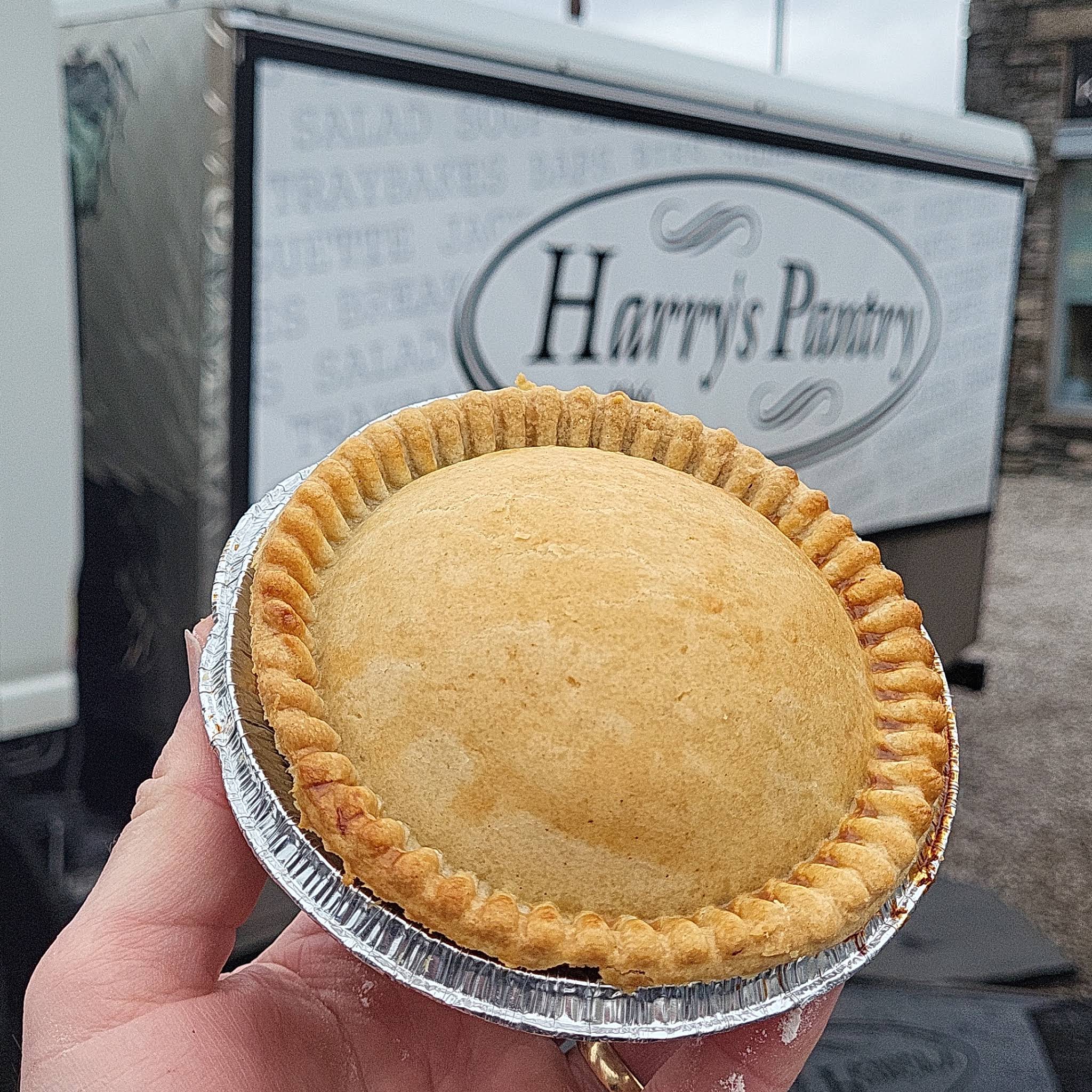 A complete Harry’s Pantry pie in its foil dish, held in front of the shop’s name